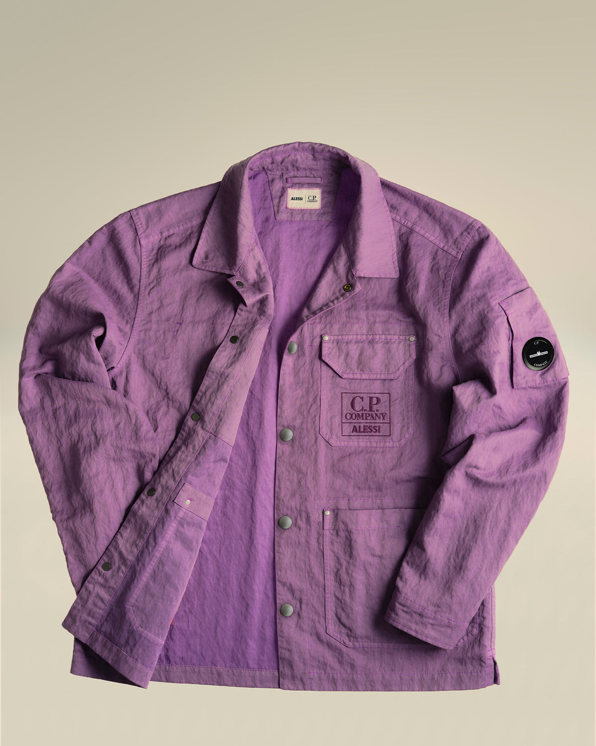 Lavender lightweight utility jacket by Alessi, with a crinkled texture, front snap buttons, chest and sleeve pockets, and co-branded logos.