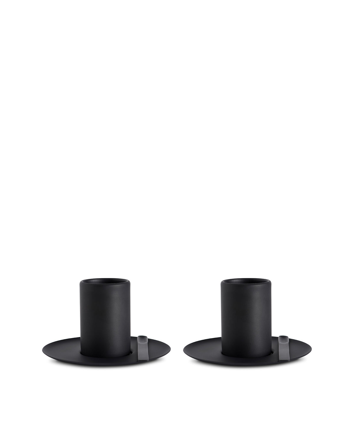 Two matte black cylindrical cups by Alessi with wide flat bases and small grey tabs, placed side-by-side.