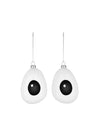 Two white, googly-eye shaped hanging decorations by Alessi, with black pupils and silver chains.