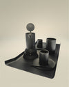 Matte black Arran tray by Alessi, featuring a unique curved edge, holding a dark coffee maker and three cups with saucers.