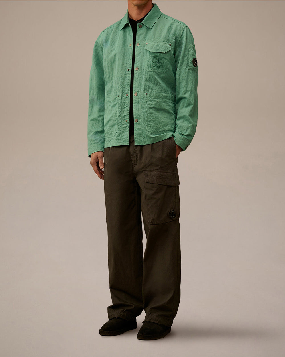 Light green lightweight jacket by Alessi with a C.P. Company pocket logo and sleeve badge, styled with dark cargo pants.