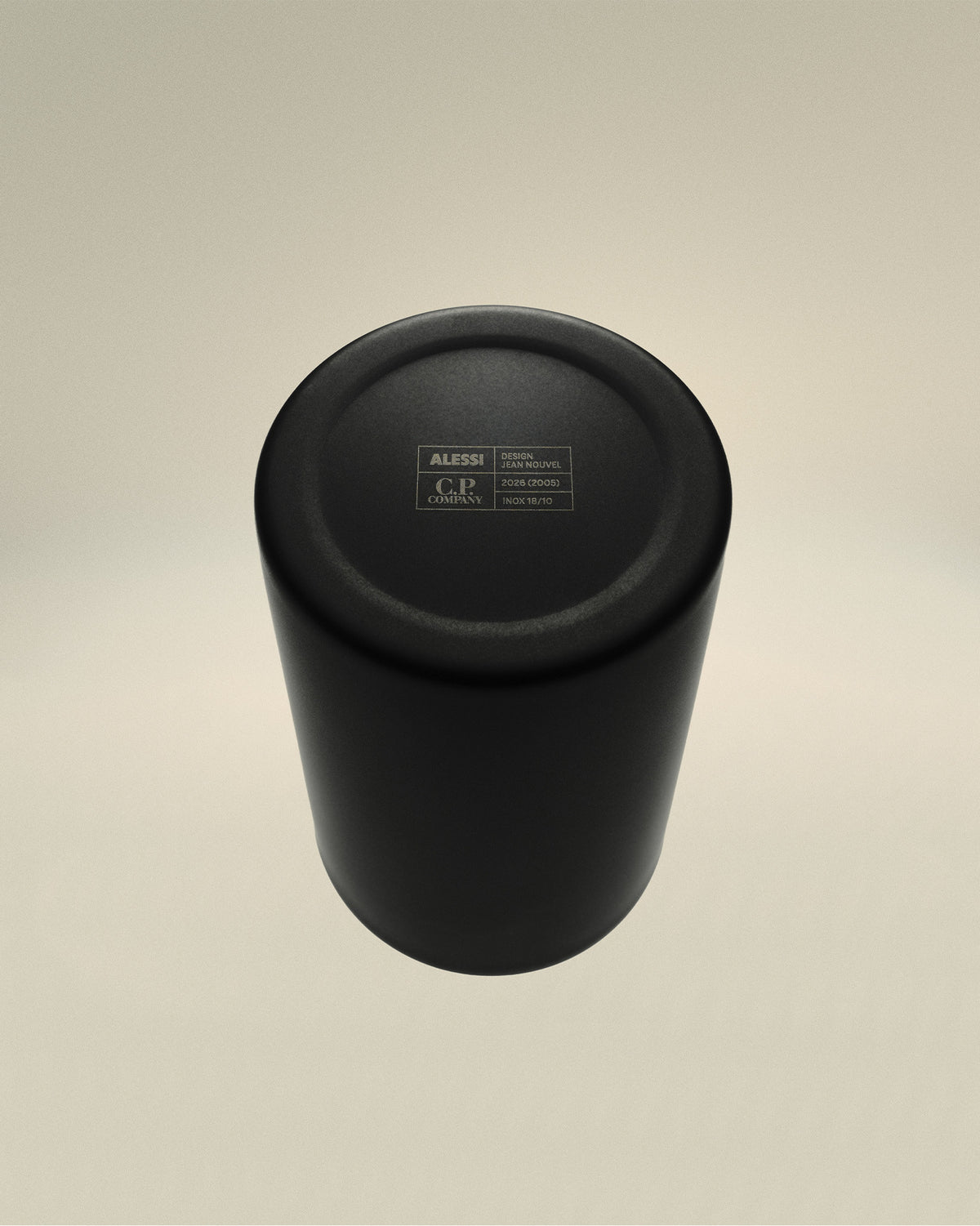 Black matte metal cup by Alessi, viewed from above, showing engraved 'C.P. Company' and 'Design Jean Nouvel' details on its base.
