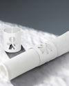 White napkin holders by Alessi with a human figure cut-out design, one holding a rolled white napkin.