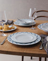 White side plate by Alessi with a blue geometric pattern, styled on a rustic wooden table.