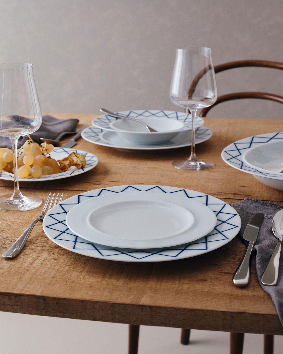 White side plate by Alessi with a blue geometric pattern, styled on a rustic wooden table.