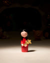 Red girl ornamental figurine by Alessi, with black hair and a gentle smile, holding a shiny gold star.