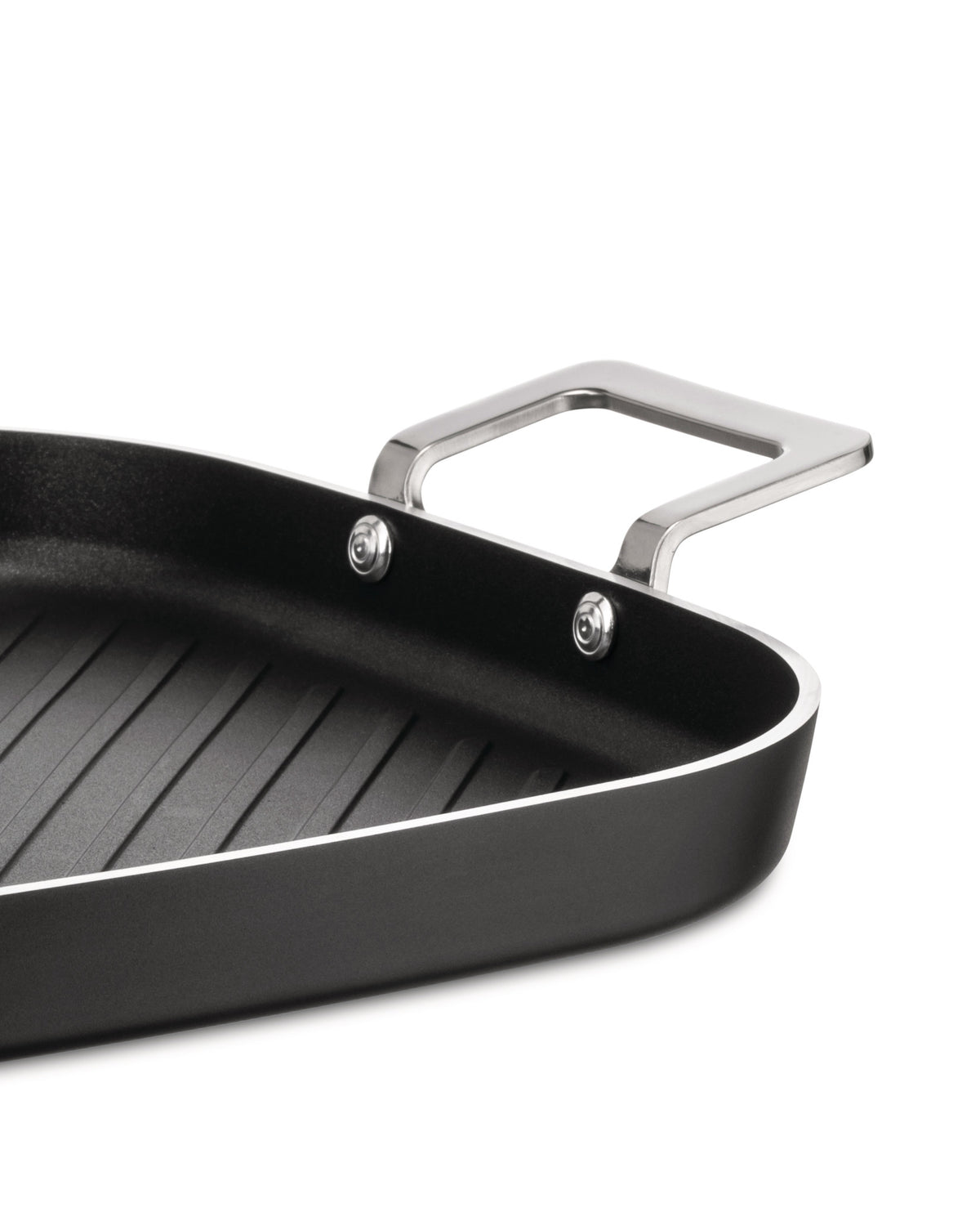 Black rectangular grill pan by Alessi with ribbed interior, silver handles, and visible rivets in a close-up angled view.