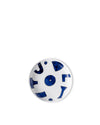 White ceramic round dish by Alessi, with abstract blue shapes and dots, on a white background.