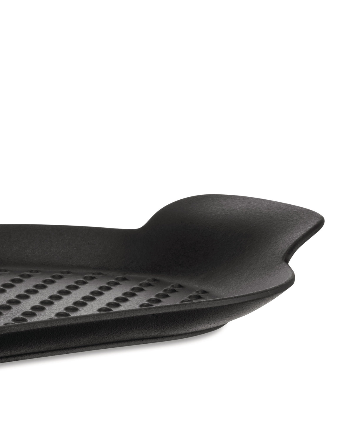 Black grill pan by Alessi, a close-up side view showing its dimpled grid pattern and curved handle.