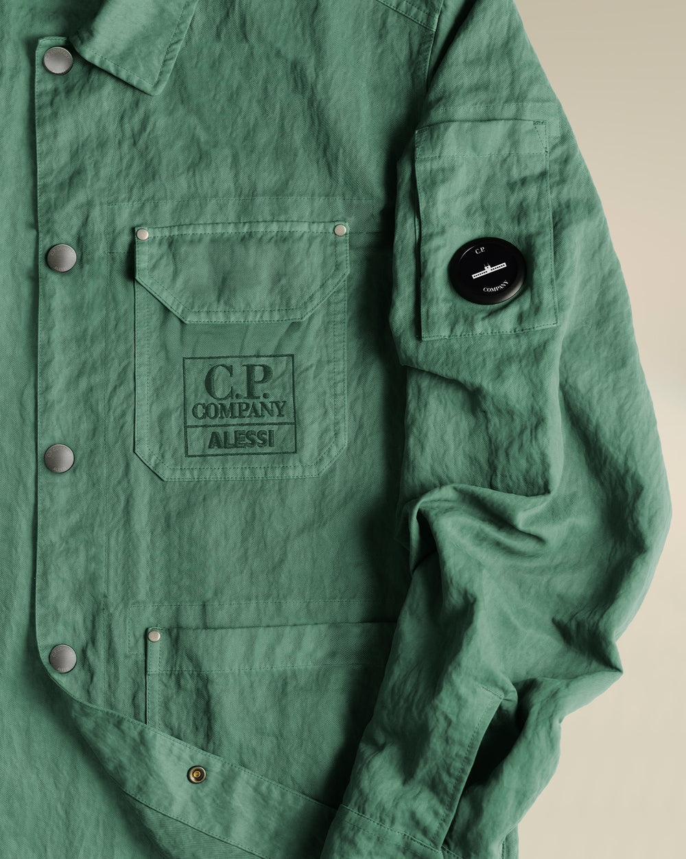 Green lightweight utility jacket by Alessi with snap buttons and prominent Alessi C.P. Company branding.