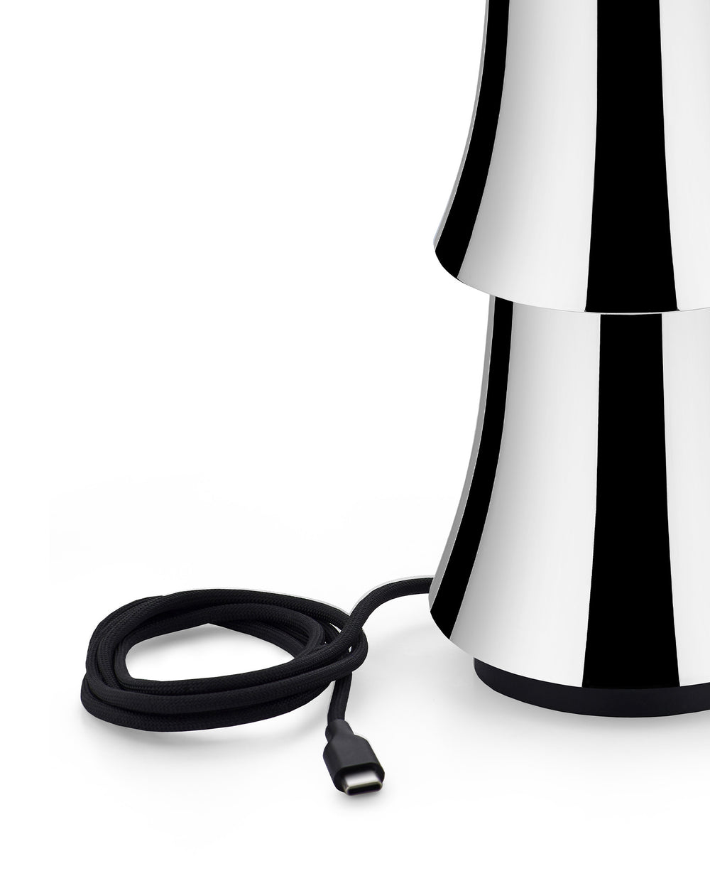 Black and white striped lamp by Alessi with a stacked, flared design and a coiled black braided USB-C cable.