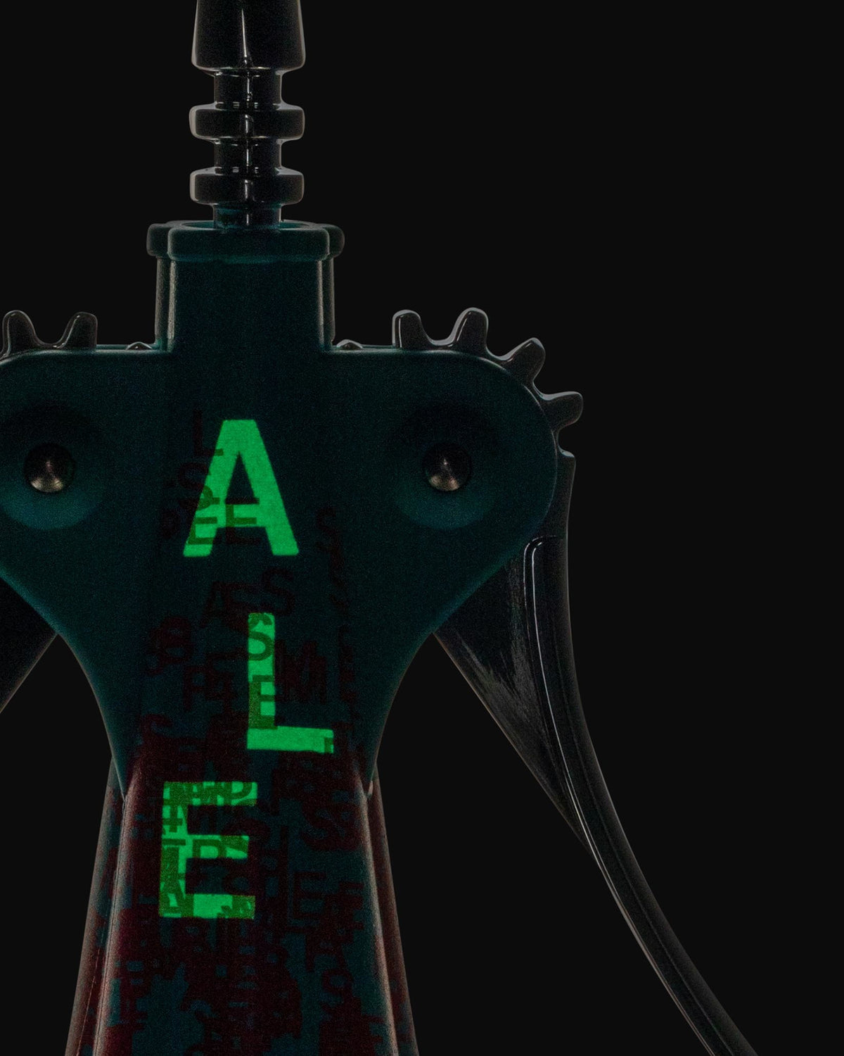 Dark teal and black corkscrew by Alessi with glowing green "ALE" letters and a subtle, textured pattern.