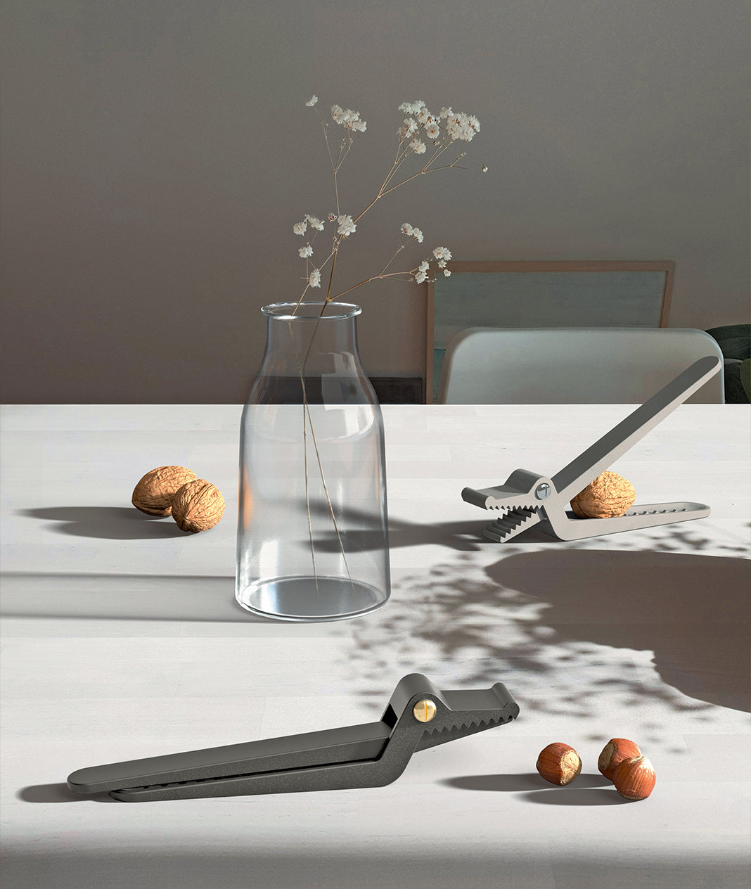 Dark gray alligator-shaped metal nutcracker by Alessi, shown open with a walnut and closed, on a white table.