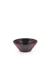 Iridescent dark purple and green metal bowl by Alessi with a ribbed, layered design.