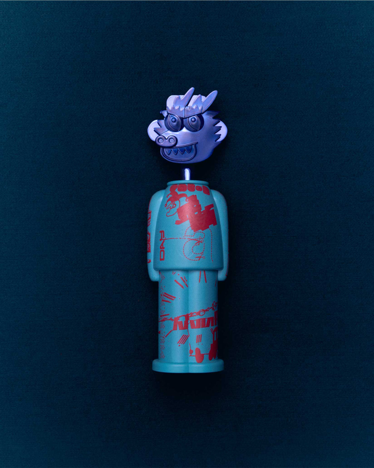 A turquoise figure corkscrew with red patterns by Alessi, featuring a detachable silver dragon head.