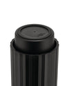 Black capsule crusher by Alessi, with a ribbed outer casing and embossed text on its smooth inner top surface.