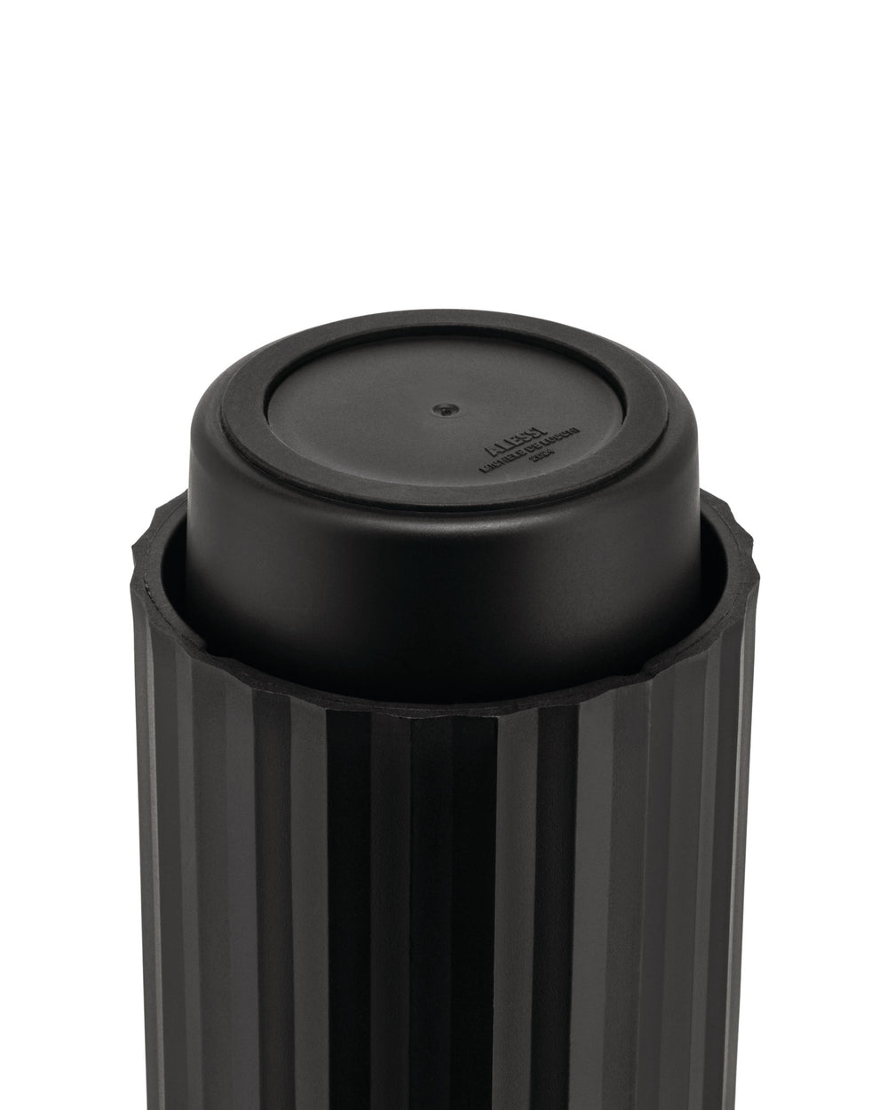 Black capsule crusher by Alessi, with a ribbed outer casing and embossed text on its smooth inner top surface.