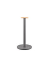 Grey metal paper towel holder by Alessi, with a light wood rectangular top and circular base.