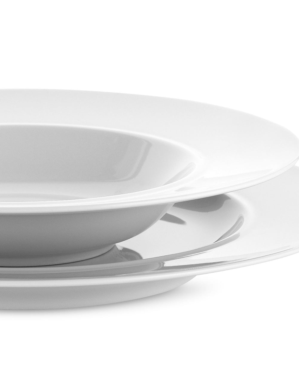 White ceramic dining plates by Alessi in a stack with a bowl, presented at an angle.