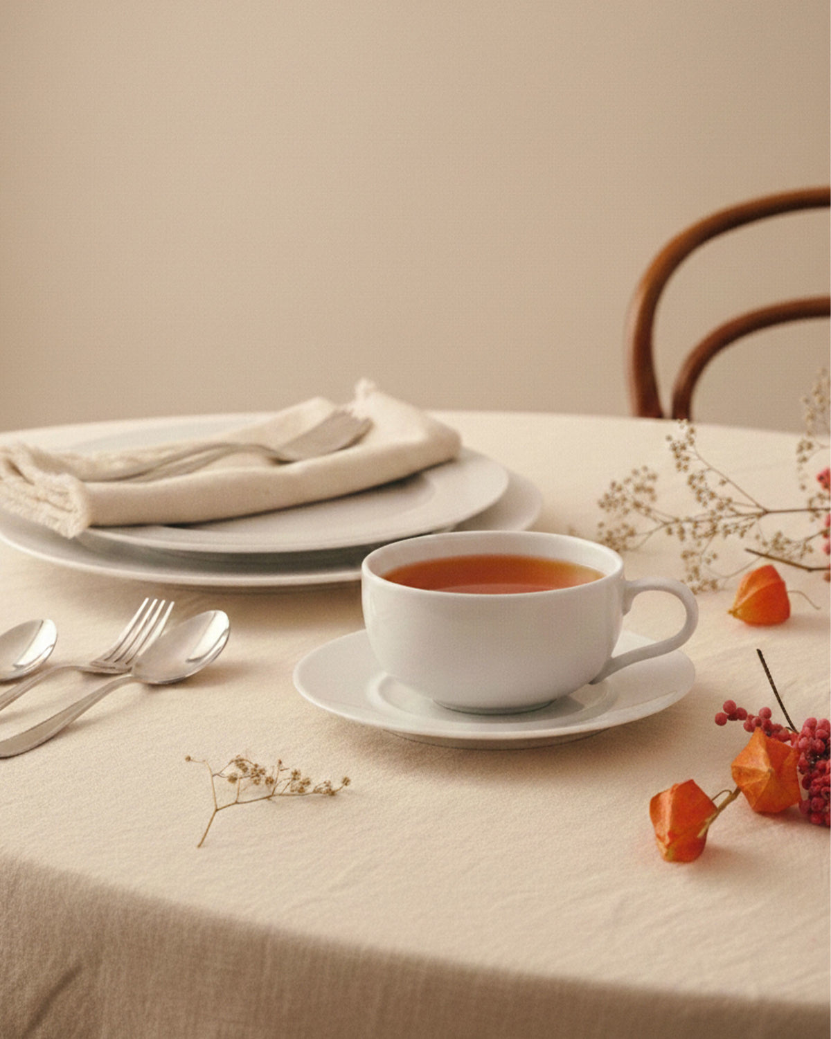 La Bella Tavola white cup by Alessi with a saucer and tea, on a neutral tablecloth with autumn decor.