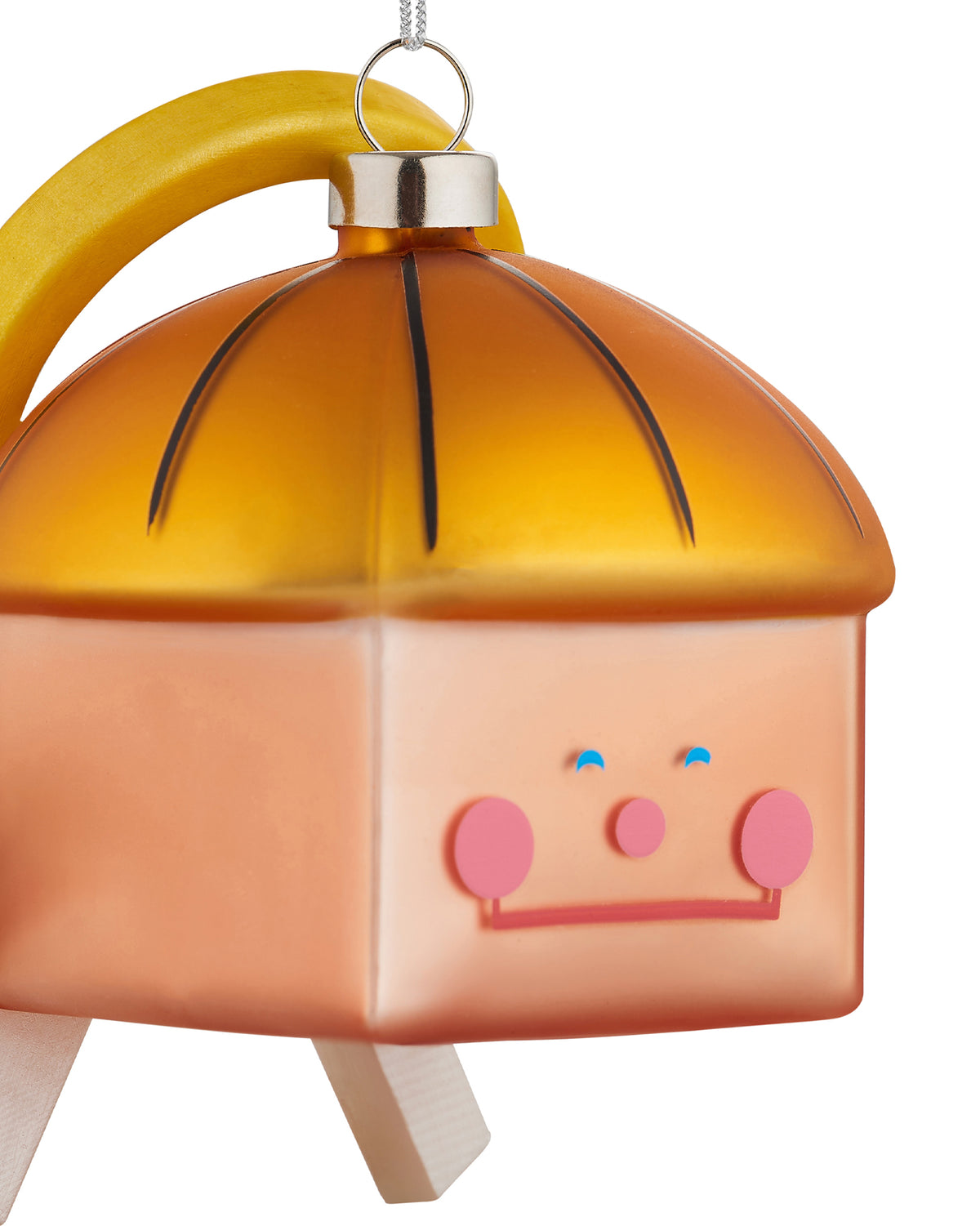Frosted orange Christmas tree ornament by Alessi with a whimsical cartoon face, yellow arched handle, and wooden legs.