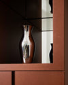 Two-tone Kuru Kuru pitcher by Alessi, with a curved bronze exterior and reflective silver interior showcasing reflections.