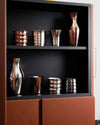 Polished Dervisci glasses by Alessi in silver and copper tones, featuring varied shapes and textures.