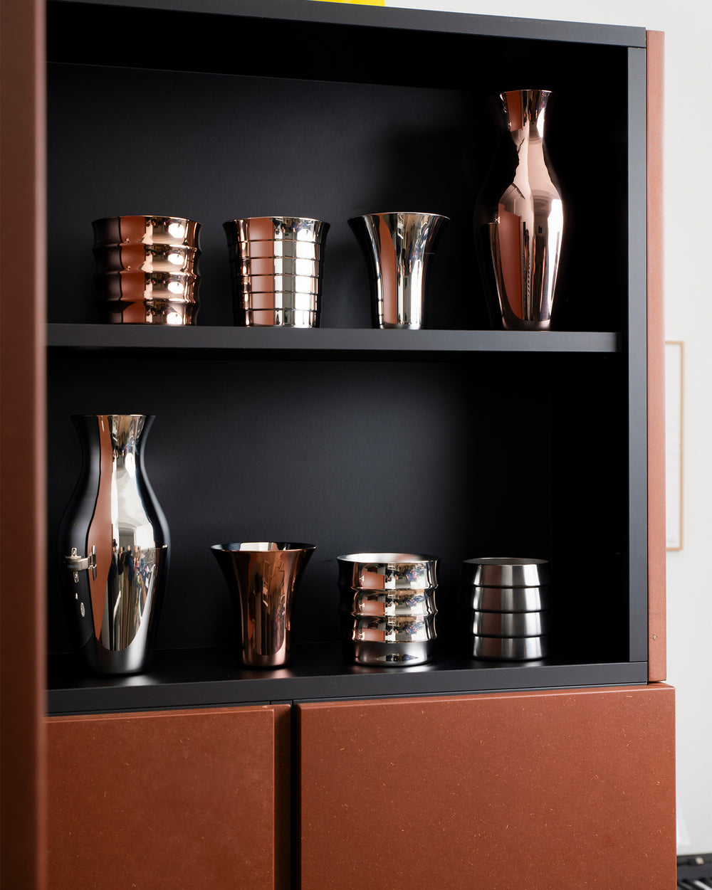Polished Dervisci glasses by Alessi in silver and copper tones, featuring varied shapes and textures.