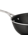 Black non-stick wok pan by Alessi with a silver handle, textured interior, and silver rim, in an angled close-up view.