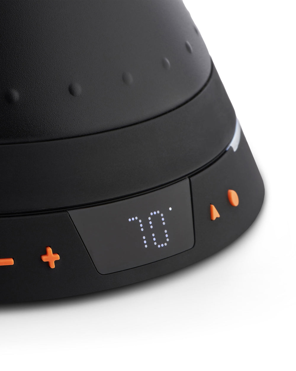 Black electric kettle by Alessi with a matte textured finish, raised dots, a digital display showing '70°', and orange control buttons, in a close-up view.