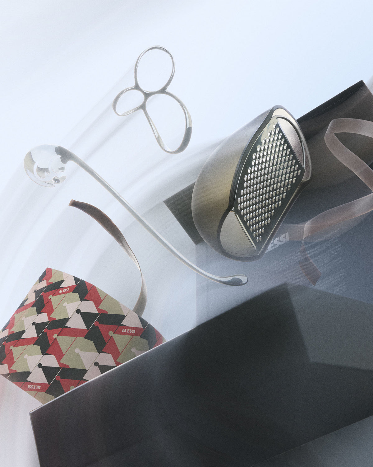 Dynamic gift set of pasta tools by Alessi, featuring a silver grater, clear pasta measure, and patterned packaging.