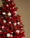 Assorted white, red, and gold Christmas tree ornaments by Alessi featuring diverse patterns like stripes, scales, and diamonds, on a red flocked tree.