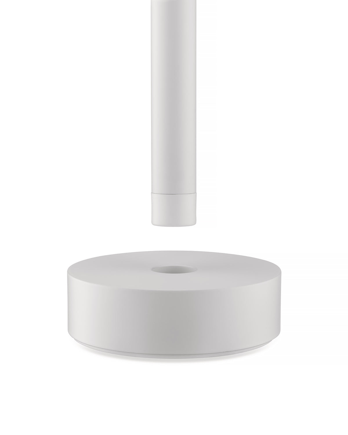 White Tsumiki lamp by Alessi, featuring a cylindrical part above a round base with a central opening.