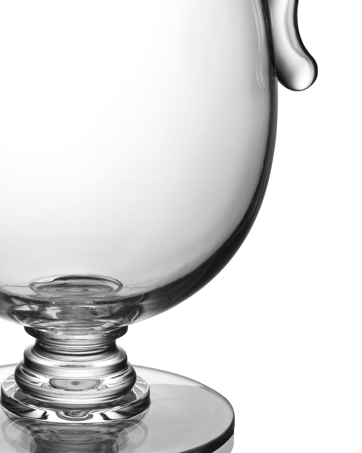 Transparent glass compote by Alessi with a ribbed stem and a pouring spout, cropped against white.