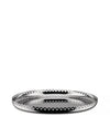 Reflective silver fruit bowl by Alessi with an intricate perforated scalloped edge design, low angle.