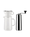 Polished chrome manual coffee grinder by Alessi, alongside a glass pour-over coffee carafe with white ceramic dripper.