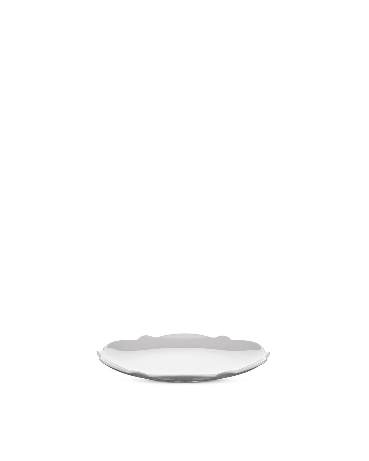White plate by Alessi with wavy, scalloped edges, angled on a white background.
