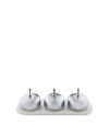 Shiny silver three-piece condiment set by Alessi with embossed container bases on a matching patterned white tray.