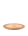 Light wood chopping board by Alessi with an ornate carved border, shown from a low angle.
