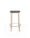 Black contoured bar stool by Alessi with light wood legs and a circular metal footrest.