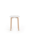 White and wood stool by Alessi with a wavy-edged white seat and natural light wood legs, front view.