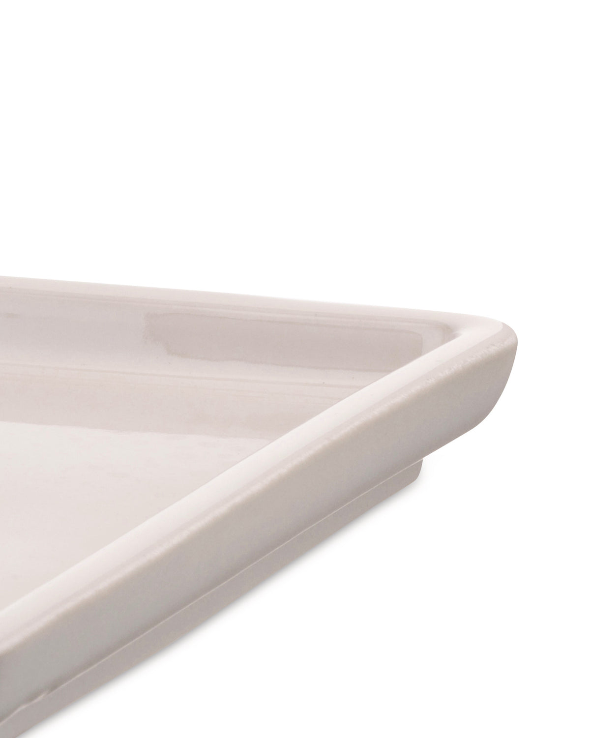 Light beige ceramic tray by Alessi, cropped close-up showing a corner and glossy finish.
