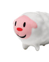 White sheep figurine by Alessi with a pink face, red nose, black eyes, and a smile, viewed from the front-side.