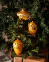 Golden Baldassarre Christmas ornament by Alessi, featuring a character design with crown details and clear gem embellishments, on a Christmas tree.