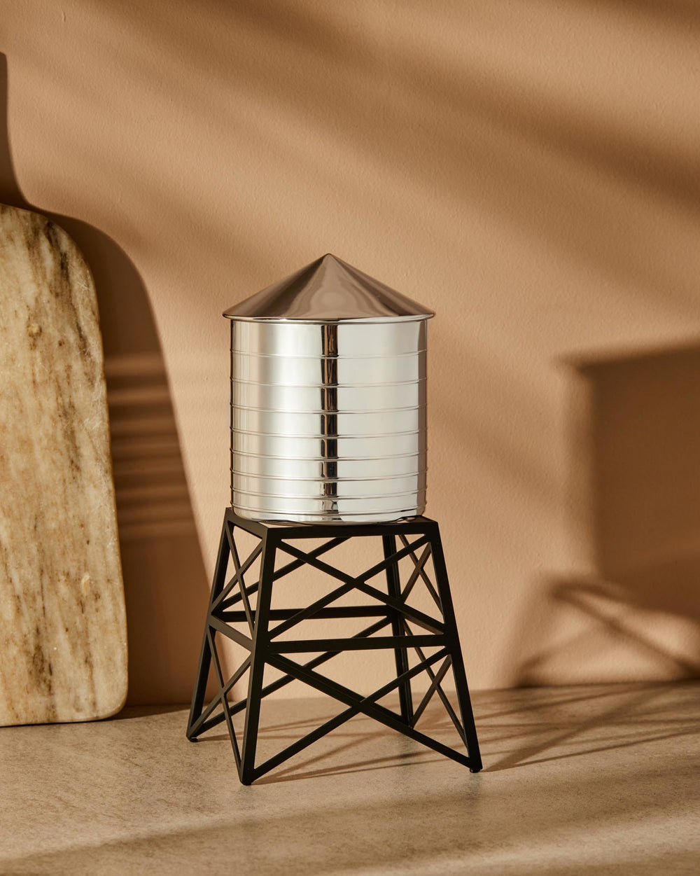 Silver metal ridged Water Tower by Alessi with a conical roof and black geometric base.