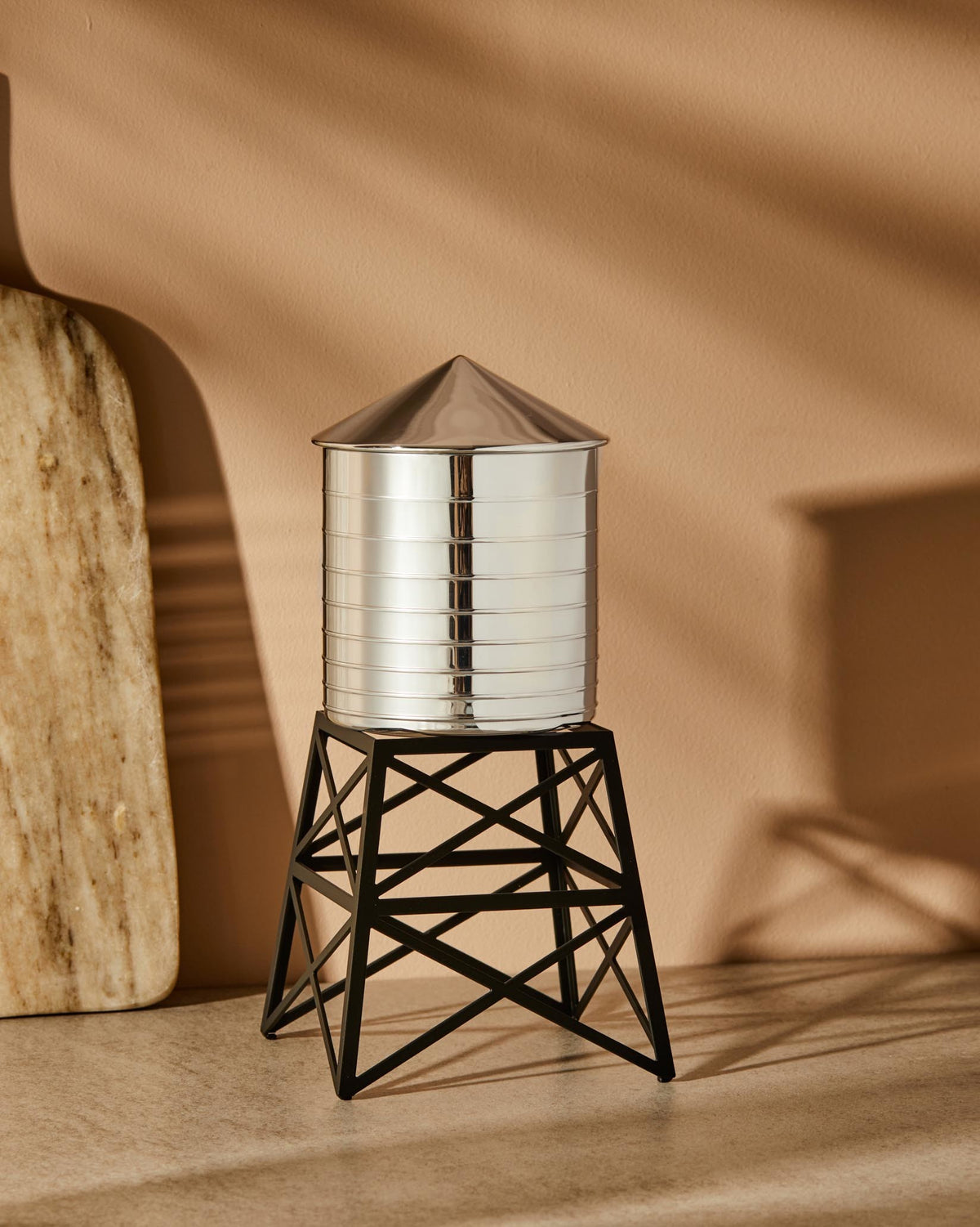Silver metal ridged Water Tower by Alessi with a conical roof and black geometric base.