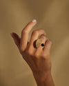 Gold-toned Edone ring by Alessi, with a fan-shaped studded design and a black spherical accent, worn on a hand.