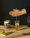 The tending box bar tool set by Alessi, with gold-toned stirrer and silver ice bucket in use.