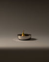 Silver fruit bowl by Alessi with a perforated scalloped edge, holding a single pear.