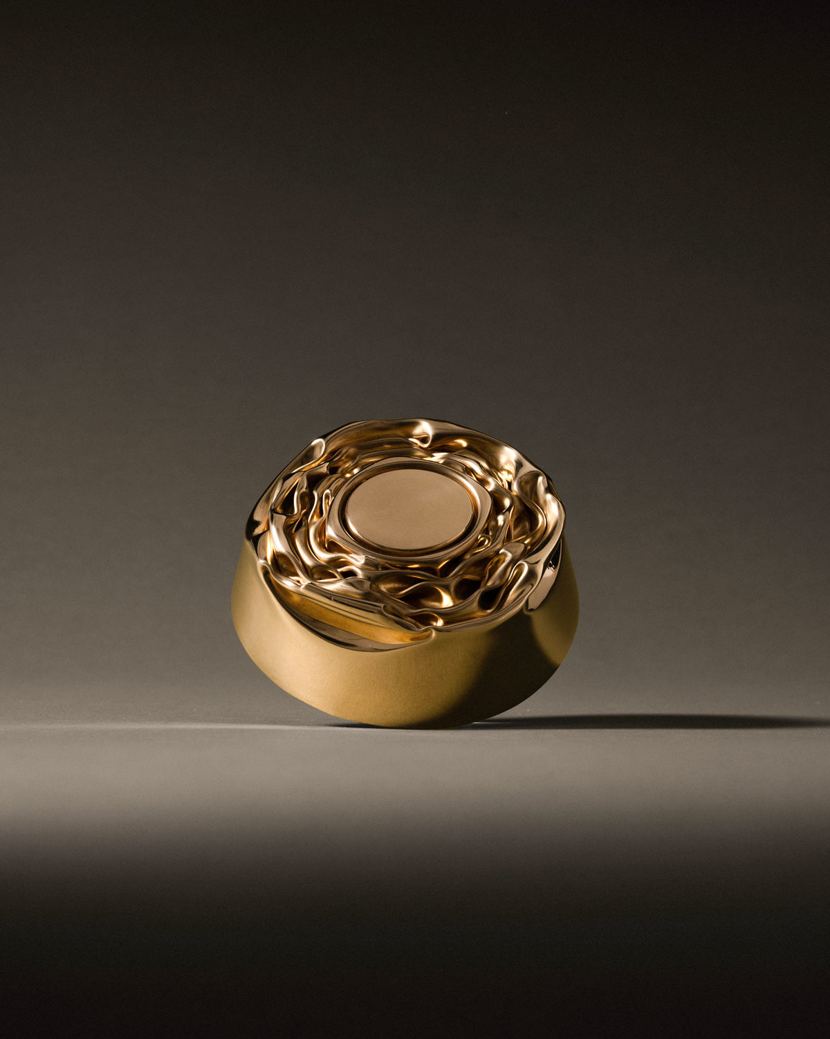 Golden metallic Compressioni container by Alessi, with a wavy, sculptural lid and smooth rounded body.